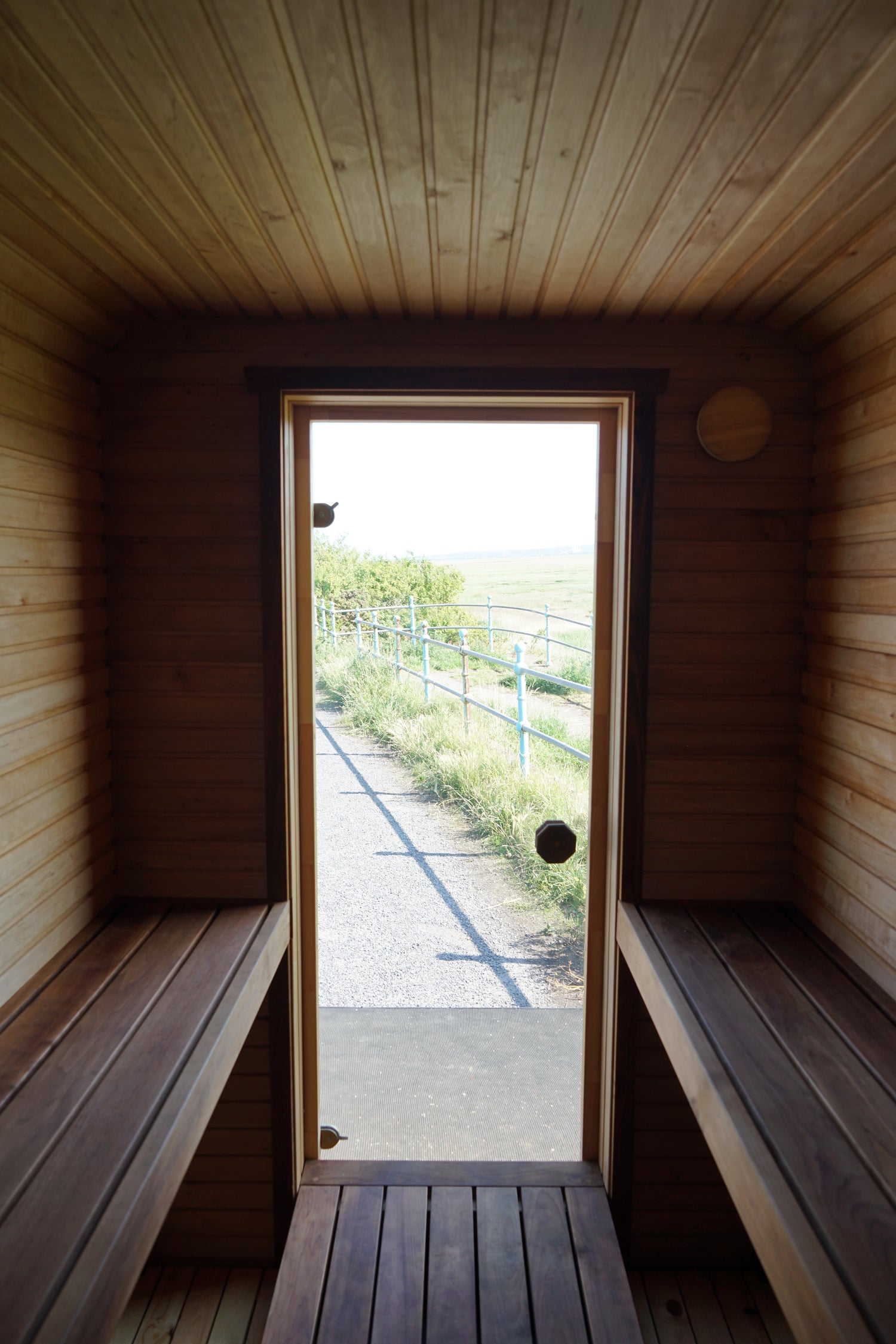 Wooden sauna with a large window showing greenery outside